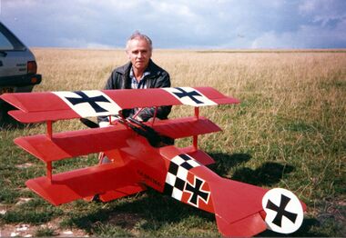 Denis Hefford in a field with his radio-controlled Fokker triplane model