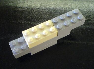 Lego vs Kiddicraft: Comparison of a ~1947 Kiddicraft Self-Locking Building Brick (white), with some modern 2012 Lego bricks (grey). Any difference in external dimensions is undetectable with a micrometer, and the two sets of bricks interlock just fine. The main difference (other than the slots) is that the Kiddicraft bricks have mildly rounded vertical edges and bobbled tops to make it easier to locate the bricks with their neighbours. The Lego bricks have flat tops (with the Lego logo), and sharp vertical edges (which makes the corners more painful when you tread on them!).